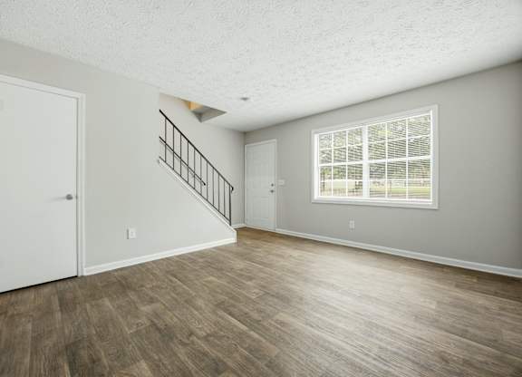 A room with a wooden floor and a staircase with a metal railing.