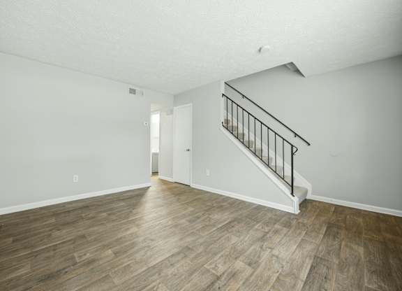 A room with wooden flooring and a staircase with metal railings.