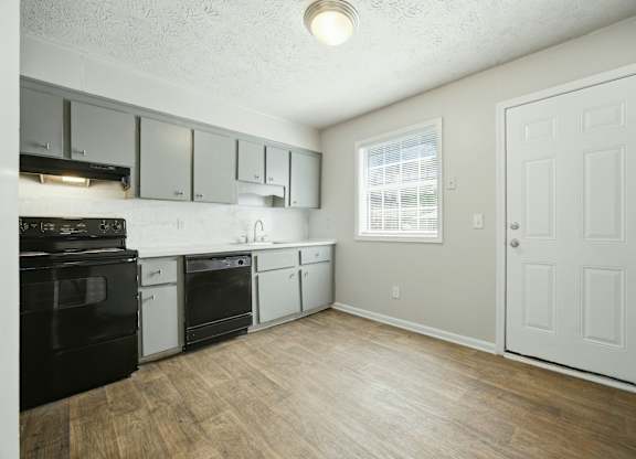 A kitchen with black appliances and white cabinets.