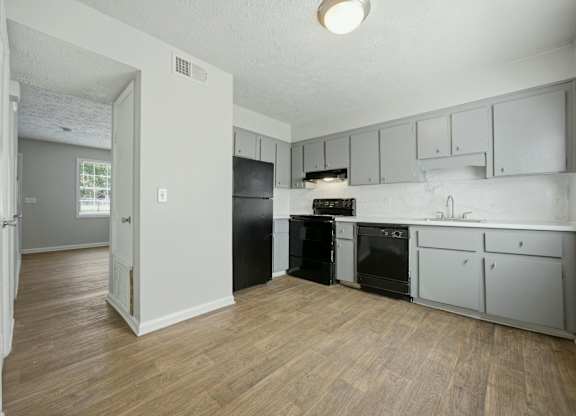A kitchen with black appliances and wooden floors.