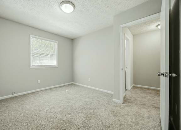 A room with a carpeted floor and a window.