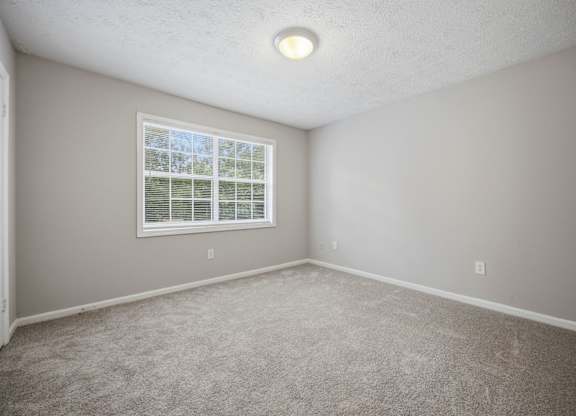 A room with a window and carpeted floor.