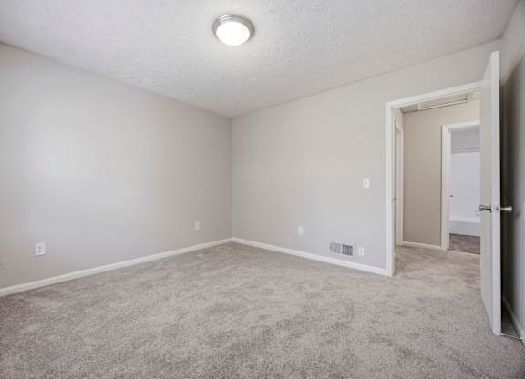 A room with a carpeted floor and a doorway leading to another room.