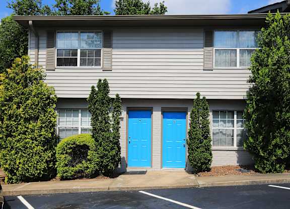 A grey building with a blue door and windows.