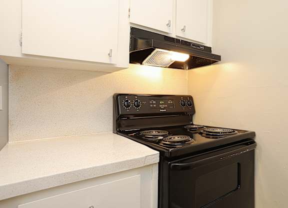 A black stove top oven with four burners and a digital display is installed in a kitchen.