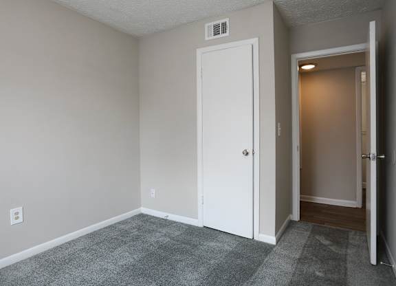 A room with a white door and a carpeted floor.