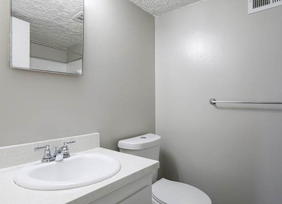 A white sink with a mirror above it and a toilet behind it.