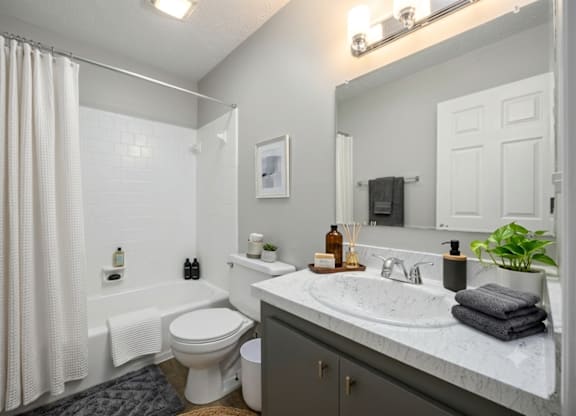 A bathroom with a white toilet, sink, and shower curtain.