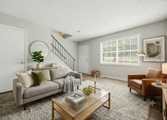 A living room with a couch, a chair, a coffee table, and a plant.