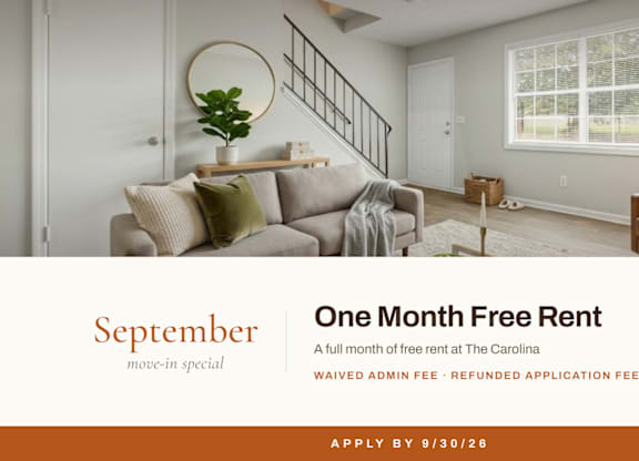 A living room with a couch, chair, and a plant on a table with a sign offering a free rent for September.