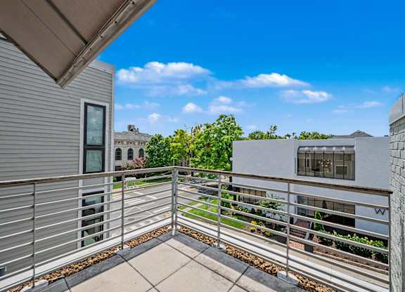 A balcony with a metal railing and a concrete floor overlooks a street.