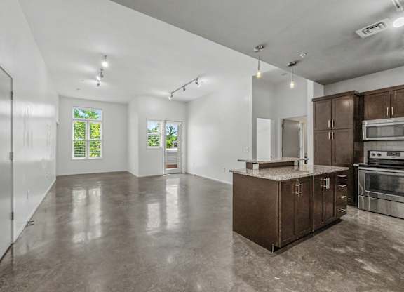 A spacious kitchen with brown cabinets and a concrete floor.
