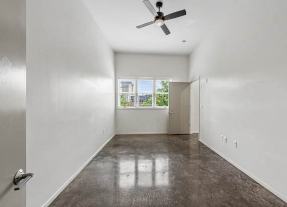 A room with a ceiling fan and a door leading to a balcony.