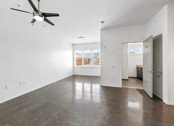 A room with a ceiling fan and a concrete floor.
