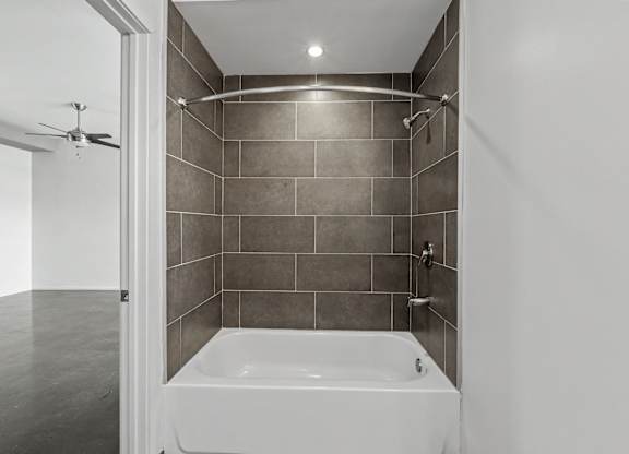 A white bathtub is in a bathroom with grey tiles.