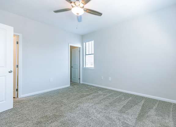A room with a ceiling fan and carpeted floor.