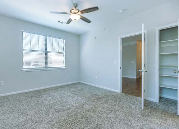 A room with a ceiling fan and a window with blinds.