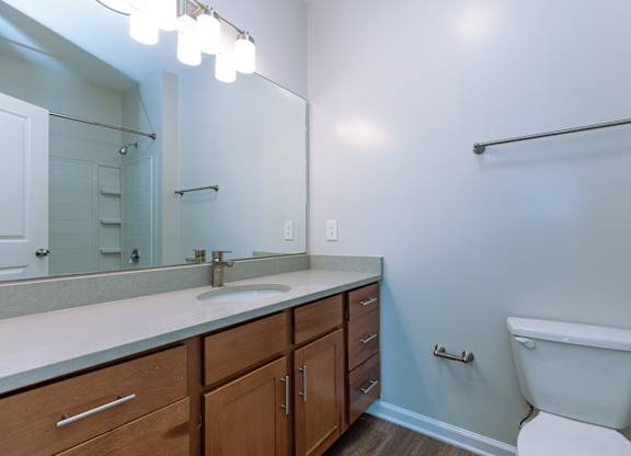 A bathroom with a toilet, sink, and mirror.