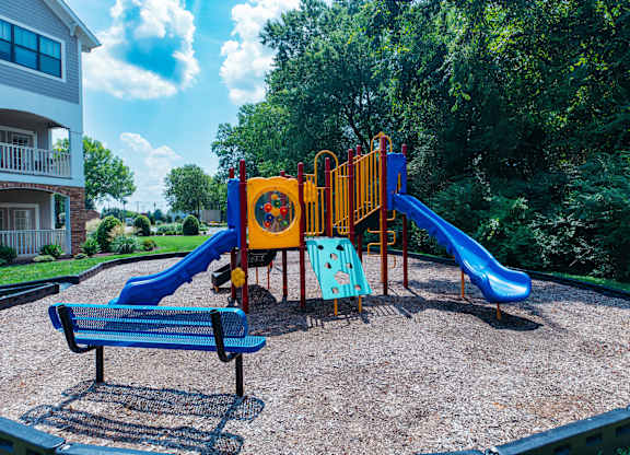 A playground with a blue slide and a yellow and red play structure.