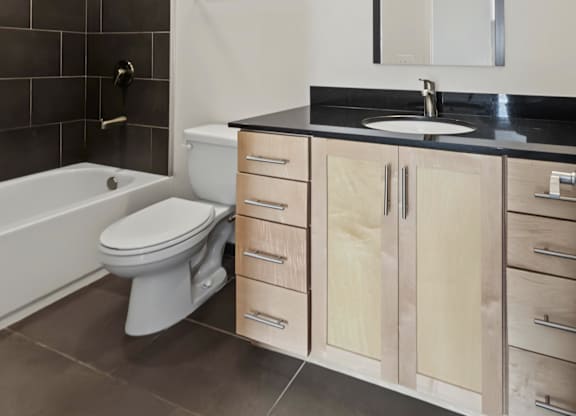A modern bathroom with a white toilet and a black countertop.