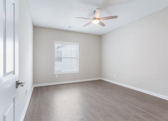 A room with a ceiling fan and a window with blinds.