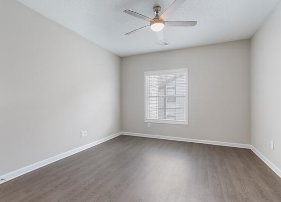 A room with a ceiling fan and a window with blinds.