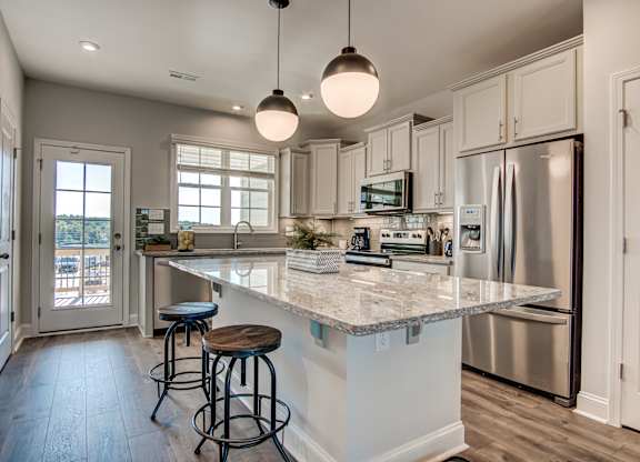 an open kitchen with a large island with three stools