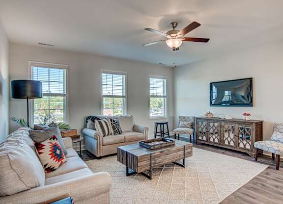 a living room with a ceiling fan and couches