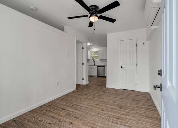 a living room with white walls and a ceiling fan