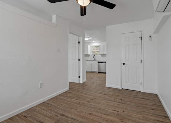 an empty living room with white walls and a ceiling fan