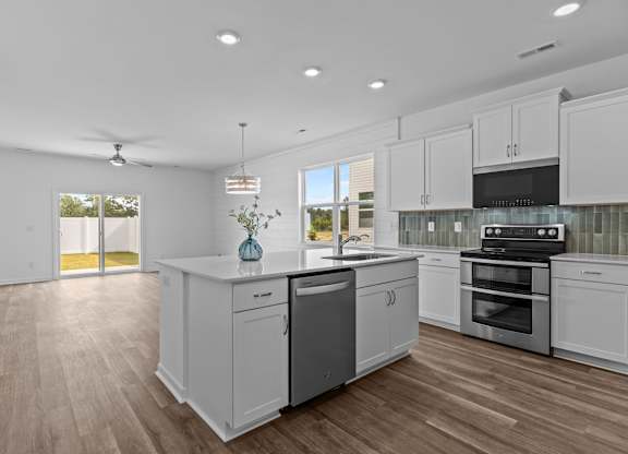 A modern kitchen with white cabinets and a wooden floor.
