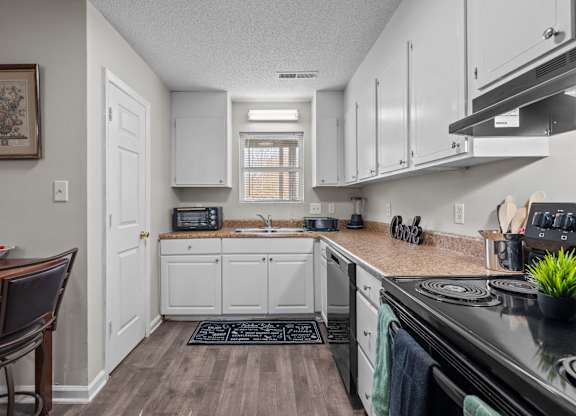 A kitchen with white cabinets and a black stove top.