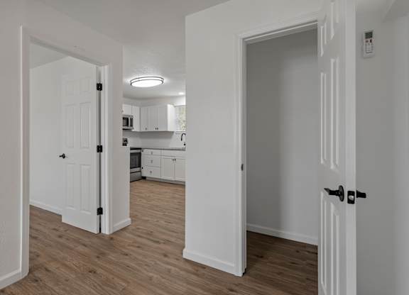 a renovated living room and kitchen with white walls and wood flooring