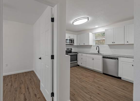 an empty kitchen with white cabinets and stainless steel appliances