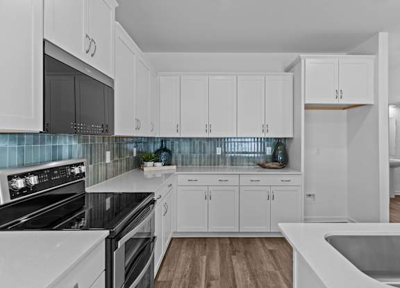 A kitchen with white cabinets and a black stove top oven.