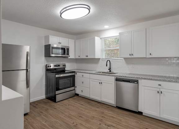an empty kitchen with white cabinets and stainless steel appliances