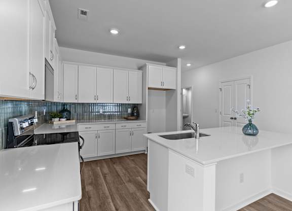 A modern kitchen with white cabinets and a large island.