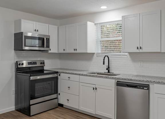 a kitchen with white cabinets and stainless steel appliances and a sink