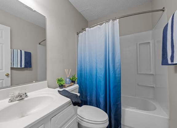 A white bathroom with a blue shower curtain.