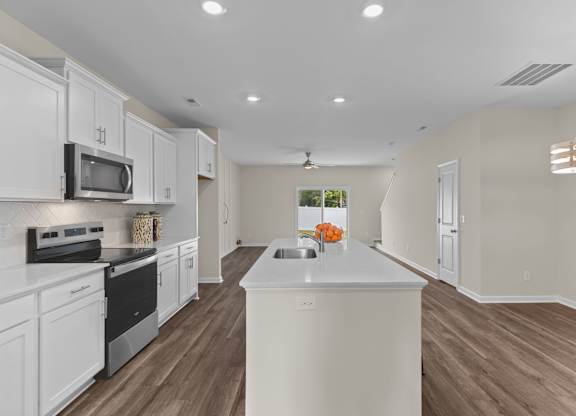 A kitchen with white cabinets and a white island.