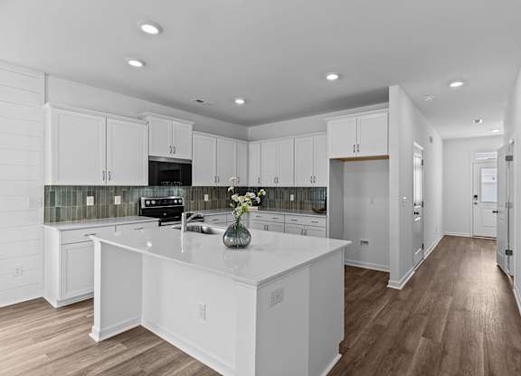 A kitchen with white cabinets and a wooden floor.