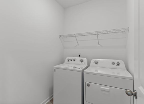 a white laundry room with two washes and a dryer