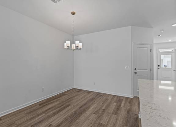 A room with wooden flooring and a chandelier hanging from the ceiling.
