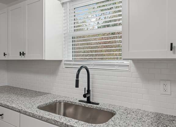 a kitchen with white cabinets and a sink and a window