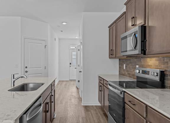 A kitchen with a sink, stove, and microwave.