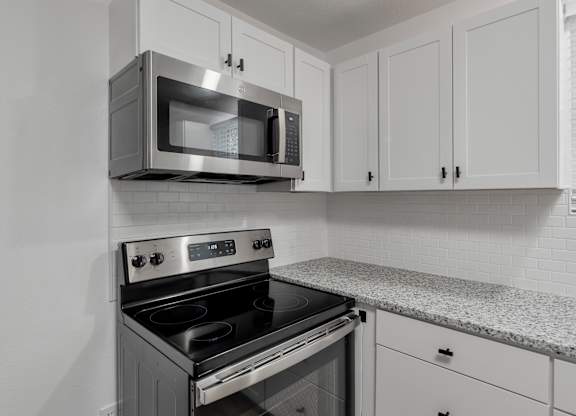 a kitchen with white cabinets and a stove and a microwave