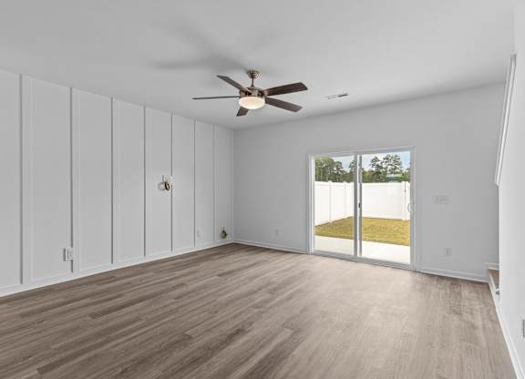 A room with a ceiling fan and sliding glass doors.