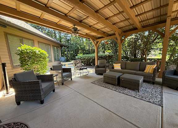 A covered patio with furniture and a ceiling fan.