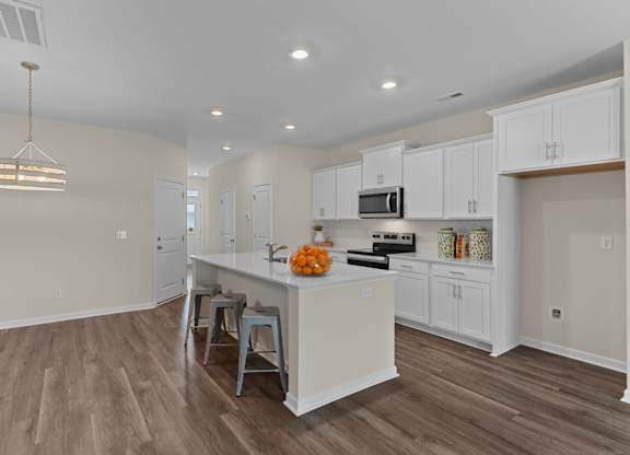 A kitchen with white cabinets and a wooden floor.
