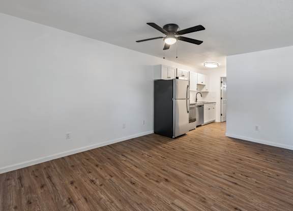 A room with a ceiling fan and wooden flooring.